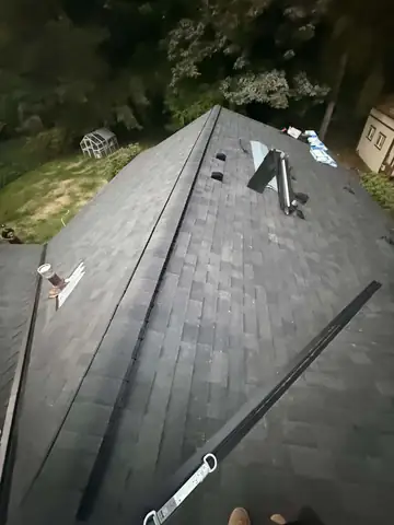 New dark shingle roof with ridge vent at dusk