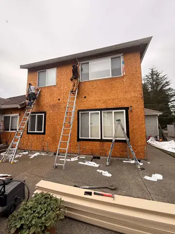 Crew on ladders over bare sheathing on a two-story home